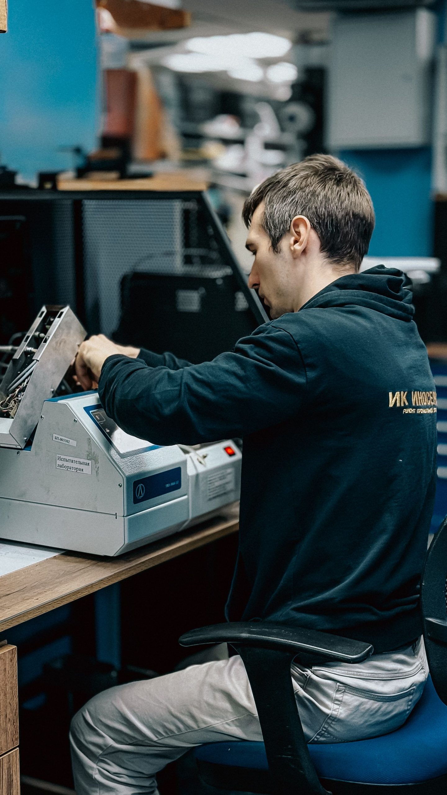 gallery-4 A man working at a printer machine in an office setting, focusing on technical tasks.