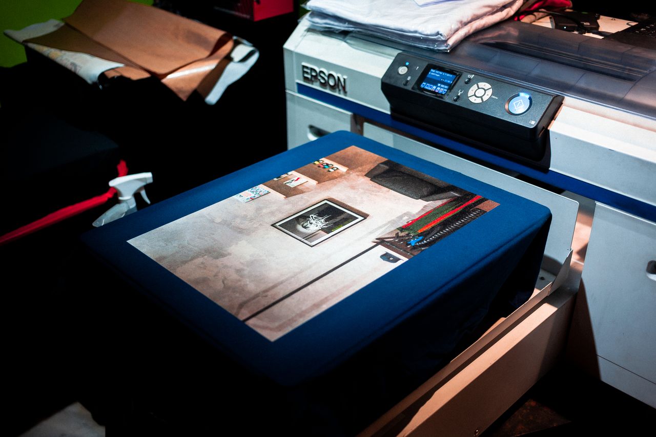 gallery-5 Close-up of a professional printer printing a custom artwork design on fabric in a studio setting.
